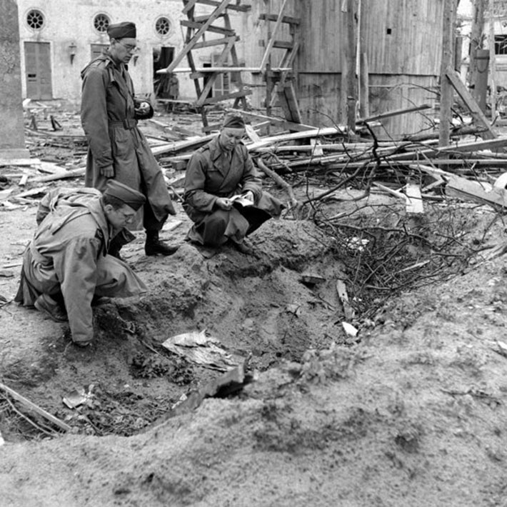 LIFE correspondent Percy Knauth, left, sifts through debris in the shallow trench in the garden of the Reich Chancellery where, Knauth was told, the bodies of Hitler and Eva Braun were burned after their suicides.